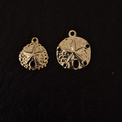 Two gold sand dollar-shaped pendants on a black background