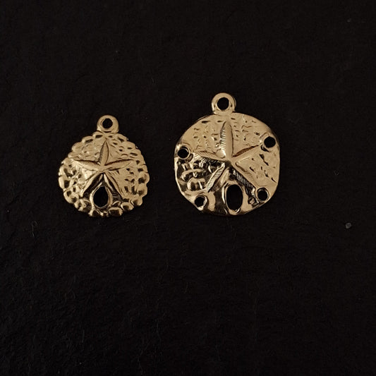 Two gold sand dollar-shaped pendants on a black background