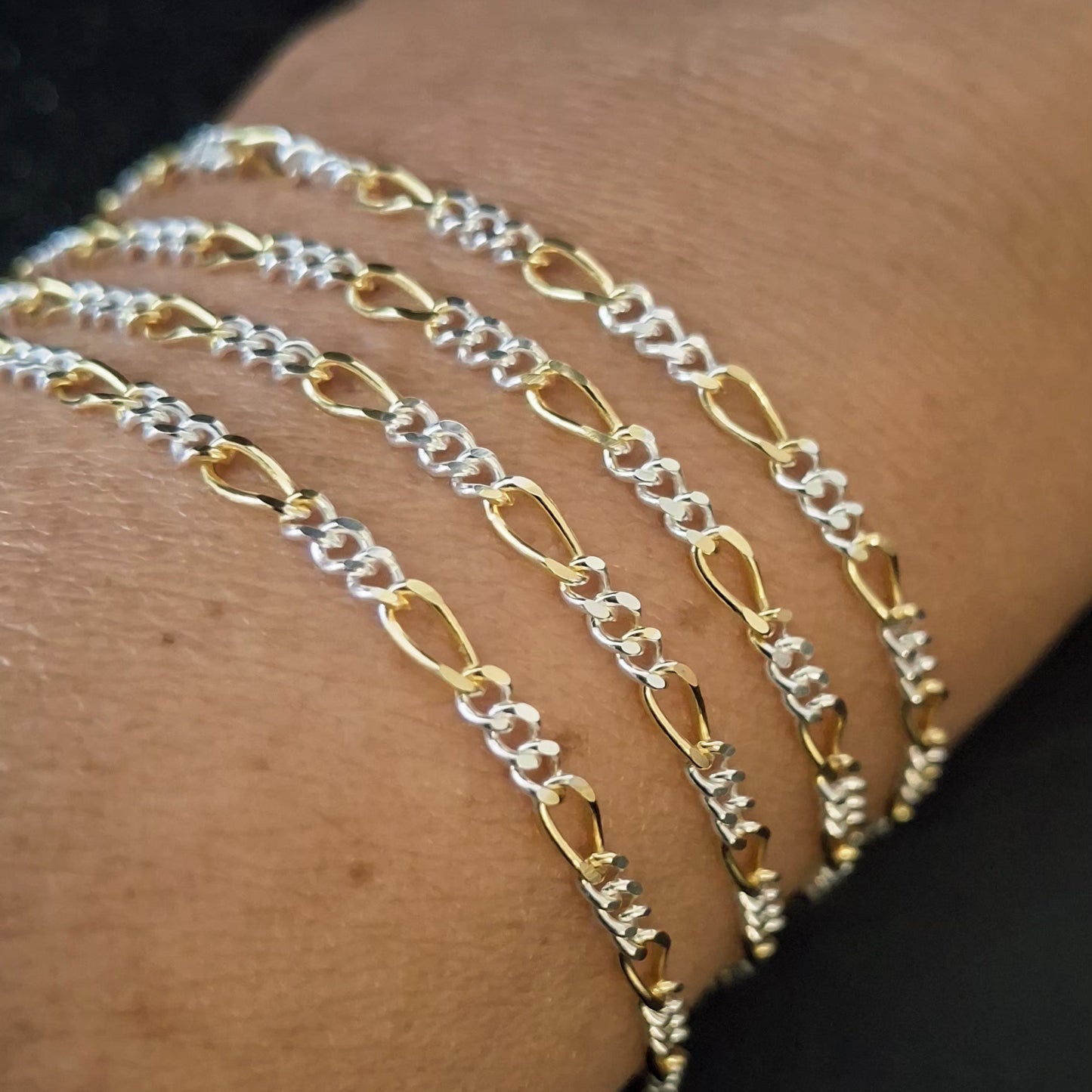2.5mm wide two-tone Figaro chain draped elegantly on a customers wrist