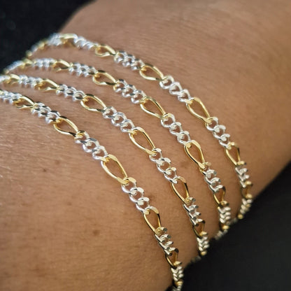 2.5mm wide two-tone Figaro chain draped elegantly on a customers wrist